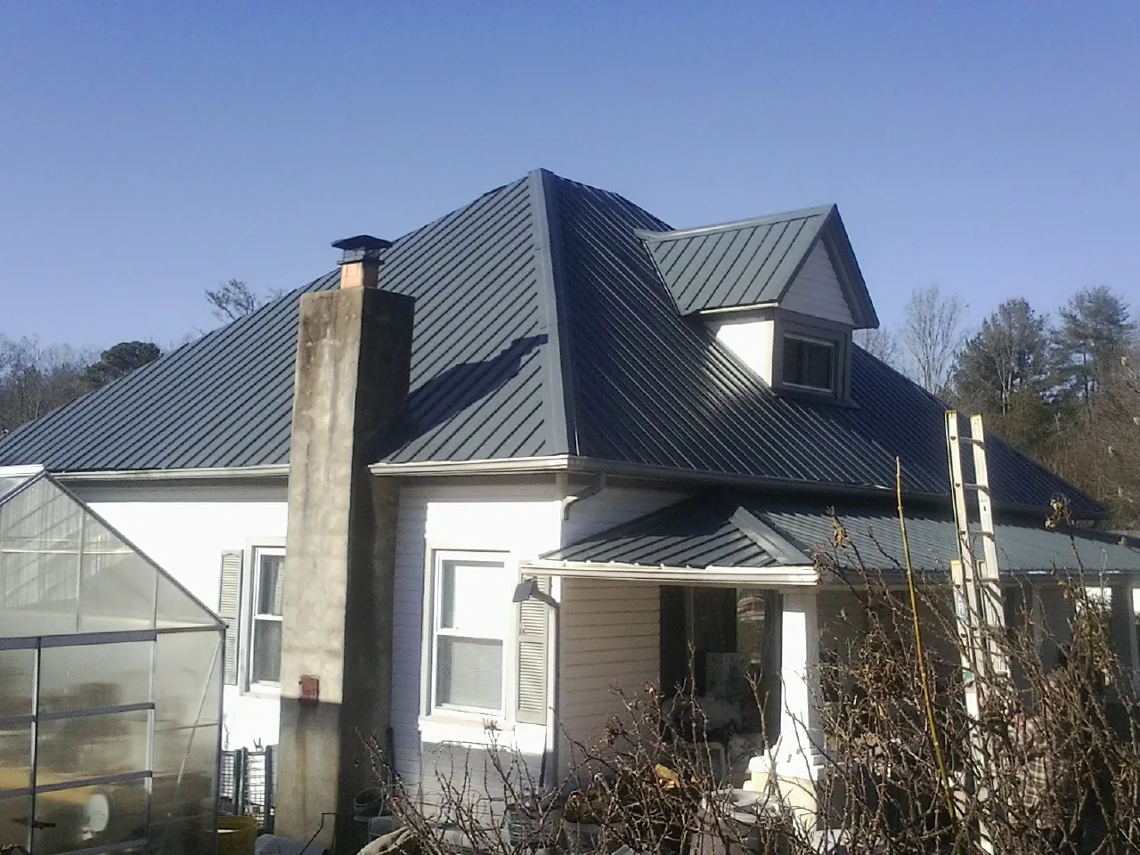 Dark blue standing seam metal roof on a white farmhouse with dormer — Slate & Tile Roof Repair by Roofing Brothers in North Adams