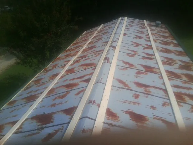 Rusted metal roof panels with new wood purlins before replacement in North Adams