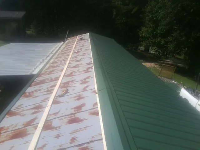 Old rusted panels beside newly installed green metal roofing — Wind Damage Roof Repair by Roofing Brothers in North Adams