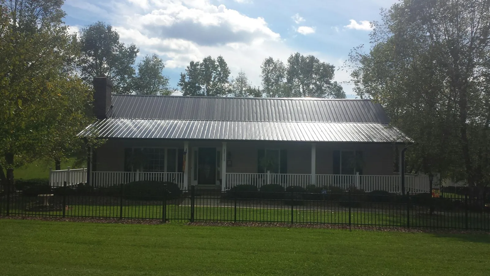 Gray metal roof on a brick ranch with a full width front porch — Gutter Guard Installation work by our crew in North Adams