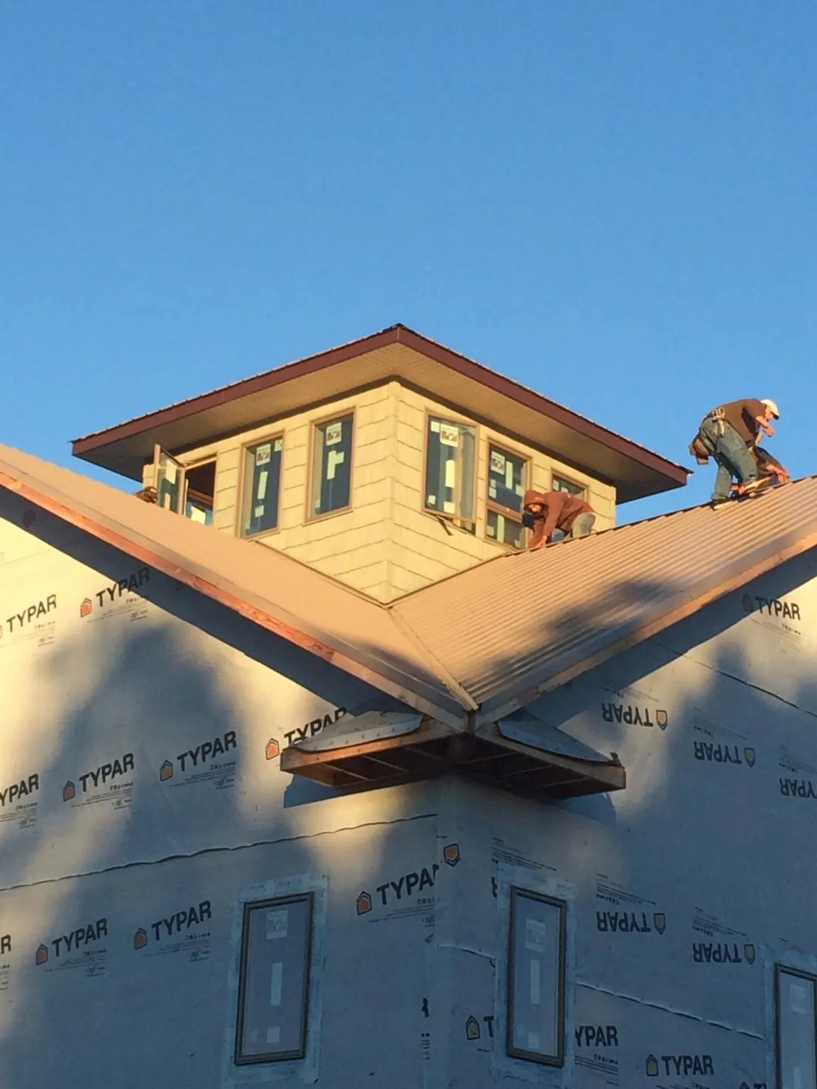 Roofers working around a rooftop cupola on a new metal roof at sunset — Roof Waterproofing in North Adams by Roofing Brothers